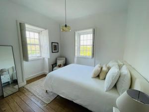 een slaapkamer met een bed met witte lakens en kussens bij Historic Douro Valley Quinta in Lamego