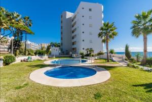a resort with a pool and palm trees and a building at Apartamento Boquerón I in Sitio de Calahonda