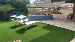 a patio with two chairs and a bench on a lawn at Lettera Luxury Apartment in Formia