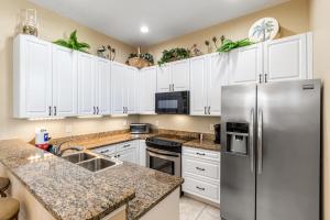 a kitchen with white cabinets and a stainless steel refrigerator at Casa Del Mar in Panama City Beach