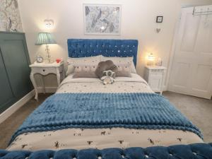 a bedroom with a blue bed with a teddy bear on it at West Wing Cottage in Sandhoe