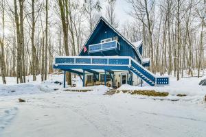 una casa blu nella neve nel bosco di 2 Mi to Schuss Mountain Cozy Cabin with Deck a Bellaire