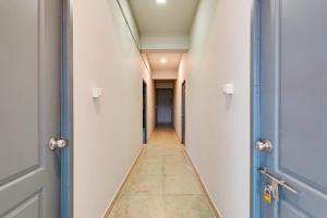 a corridor of an empty hallway with blue doors at Super Hotel O ECR Stays Near Nemmeli Beach Formerly GVS Homes in Mahabalipuram