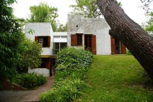 een oud wit huis met een boom ervoor bij Iemanyá in Villa Gesell