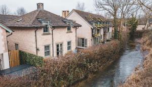 eine Reihe von Häusern neben einem Fluss in der Unterkunft Cosy Cotswold Home - Jacobs Cottage in Cirencester