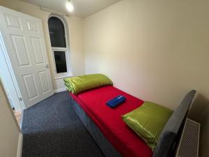 a room with a bed with a red blanket and a door at Barnsley Guesthouse in Barnsley