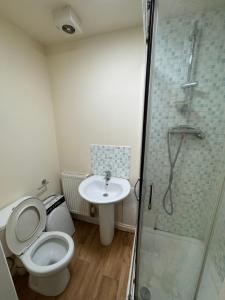 a bathroom with a toilet and a sink and a shower at Barnsley Guesthouse in Barnsley