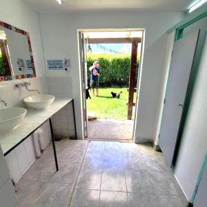 a bathroom with two sinks and a person with a dog at Lago Argentino Hostel in El Calafate