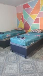 two beds in a room with a colorful wall at Nessa Familia P Frances in Marechal Deodoro