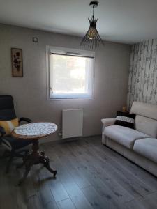 a living room with a couch and a table and a window at Appartement T3 calme avec belle vue in Poisy