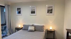 1 dormitorio con 1 cama con 2 mesitas de noche y 2 velas en Downtown Mt Beach Apartment, en Mount Maunganui