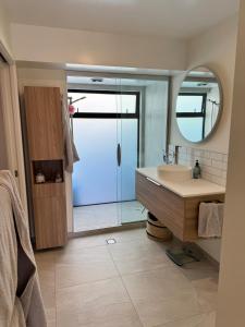 Un baño con ducha, lavabo y espejo. en Downtown Mt Beach Apartment, en Mount Maunganui 11 fotos más