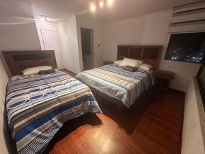 a bedroom with two beds and a flat screen tv at Acogedor Departamento in Iquique