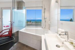 Un baño con bañera, lavabo y ventana. en Best Western Hotel Rebstock, en Rorschacherberg