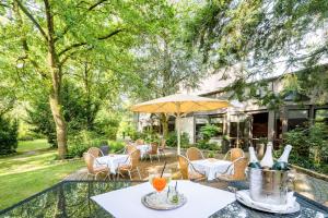 a patio with tables and chairs and an umbrella at Best Western Hotel Der Föhrenhof in Hannover