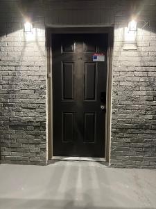a black door with two lights on a brick wall at Queen Suite - Attached Bath - Home Theater - Home Tub in Forest Park