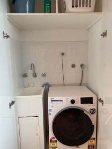 a washing machine in a small kitchen with a sink at Beach Holiday Home-Close to Airport-3 Bed & 2 Bath in Lauderdale