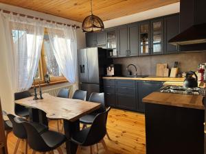 a kitchen with black cabinets and a wooden table at Dom w górach Saganówka Beskidy in Międzybrodzie Bialskie