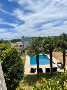 a swimming pool with two palm trees and a building at Ayres de chajari in Chajarí