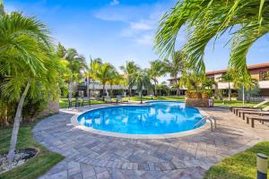 a swimming pool with palm trees and benches around it at 2 Min Walk To Eagle Beach W Pool, Gym & Spa in Palm-Eagle Beach