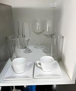 ein weißes Regal mit Weingläsern und Tassen darauf in der Unterkunft "1103 - Studio Moderno e Completo no Campo Belo!" in São Paulo