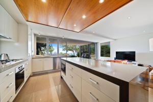 Una cocina abierta con gabinetes blancos y una isla grande. en Waves #1 by Discover Stradbroke, en Point Lookout