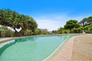 una piscina con una valla y palmeras en Waves #1 by Discover Stradbroke, en Point Lookout