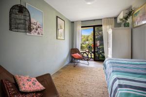 a bedroom with a bed and a chair and a window at Galleries #1 in Peregian Beach