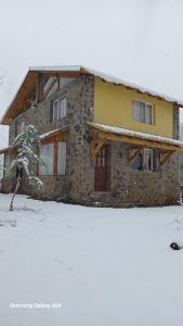 a stone house with snow in front of it at Alojamiento Küme Kiyen in Aluminé +6 photos