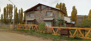 a house with a wooden fence in front of it at Alojamiento Küme Kiyen in Aluminé