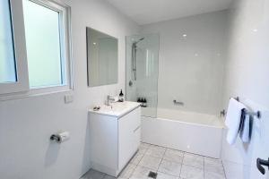 un bagno bianco con lavandino e vasca di Beautiful garden cottage in Bowral a Bowral Altre 13 foto