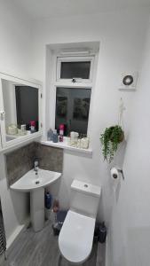 a white bathroom with a toilet and a sink at Cosy 3 Bedroom, 5 Bed House! in Headingley