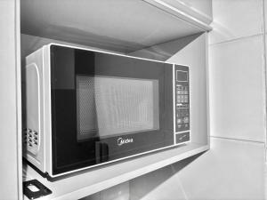 a microwave oven hanging on a wall in a kitchen at Quelônia Residence in Nossa Senhora do Livramento