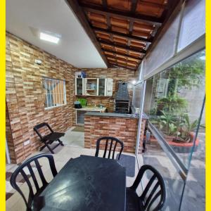 a patio with a table and chairs and a kitchen at Casa PG na Arvore Hidro Praia in Praia Grande