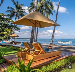 a pair of chairs under an umbrella next to the ocean at The Chandi Boutique Resort & Spa in Senggigi