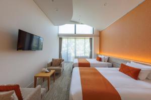 a hotel room with two beds and a flat screen tv at WeBase KAMAKURA in Kamakura
