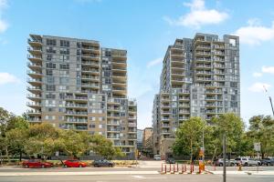 キャンベラにあるStylish 1-Bed Flat with Pool BBQ & Sauna Accessの駐車場に車を停めた高層ビル2棟