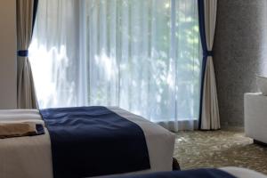 a bedroom with a bed and a large window at WeBase KAMAKURA in Kamakura