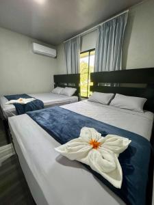 a bedroom with two beds with a flower on them at Hidden River Lodge & Termales Incluidas in San Francisco
