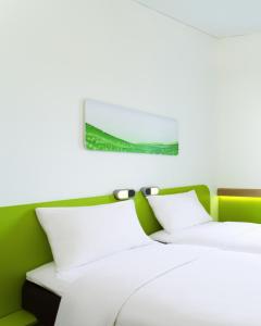 2 camas blancas en una habitación con una pared verde en Ibis Budget Bandung Asia Afrika en Bandung