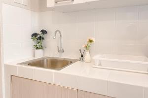 eine weiße Küche mit einem Waschbecken und Blumen in der Unterkunft Good Deal and Restful Studio at Apartment Tokyo Riverside PIK 2 By Travelio in Tangerang + 16 Fotos