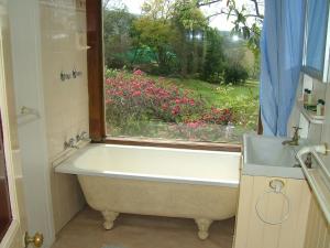 a bath tub in a bathroom with a window at Hermitage Cottage in Kurrajong