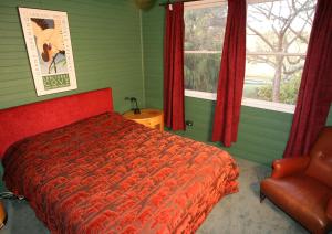 een slaapkamer met een bed, een stoel en een raam bij Hermitage Cottage in Kurrajong