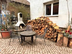 a pile of fire wood next to a table and chairs at Bett im Heu auf Bauernhof Free Wifi Schlafsack in Hausbreitenbach