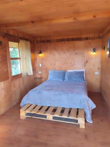 a bedroom with a bed in a wooden cabin at La madriguera de Guatavita Sta María in Guatavita