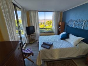 a bedroom with a bed and a balcony with a television at Amplio y hermoso departamento con vista al mar in Lilén +25 photos