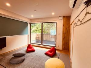 a living room with a large window and red pillows at Toraya Attic in Shimoda