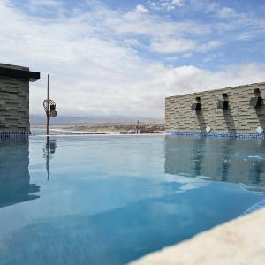a swimming pool with blue water in front of a building at EL FARO HOTEL in Chala