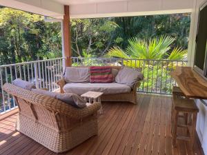 a porch with wicker chairs and a couch at Forest Tangle Retreat, Two Bedroom in Diddillibah