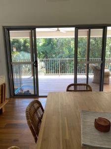 a dining room table and chairs with a view of a deck at Forest Tangle Retreat, Two Bedroom in Diddillibah